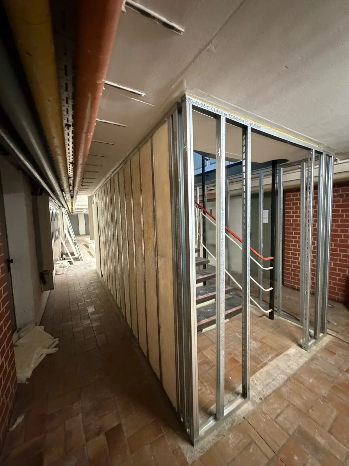 Offene Metallständerwand mit teilweise eingelegter Dämmung an einer Treppeneinhausung