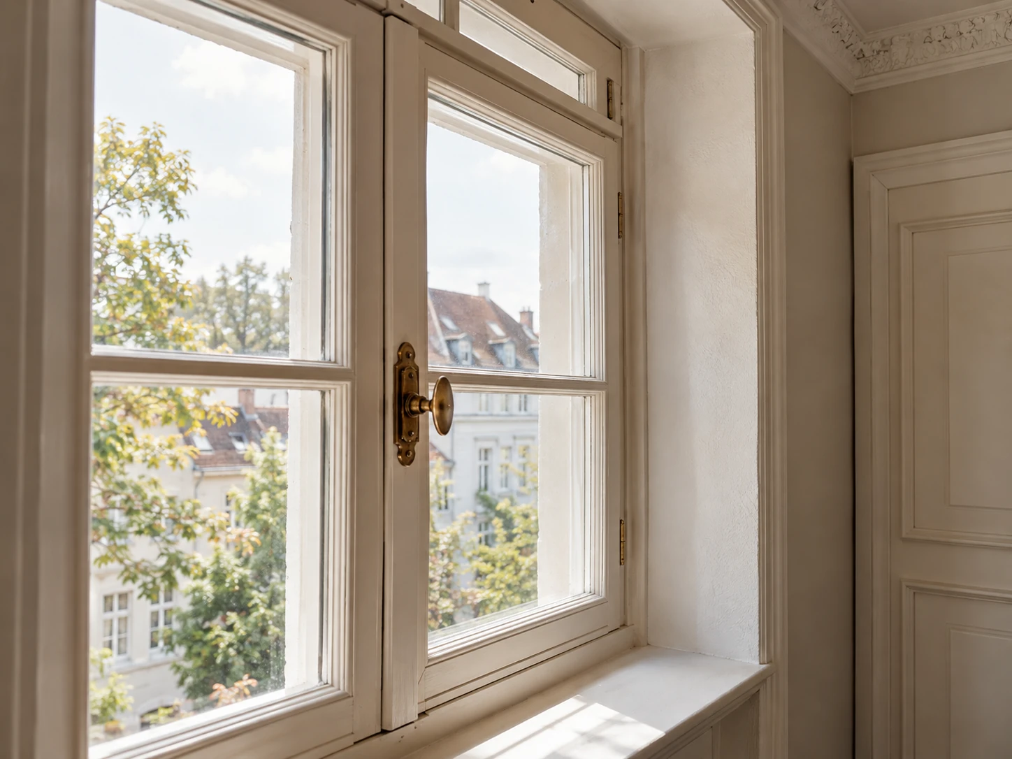 Behutsam erneuertes historisches Holzfenster mit Messinggriff und schlichtem Deckenstuck
